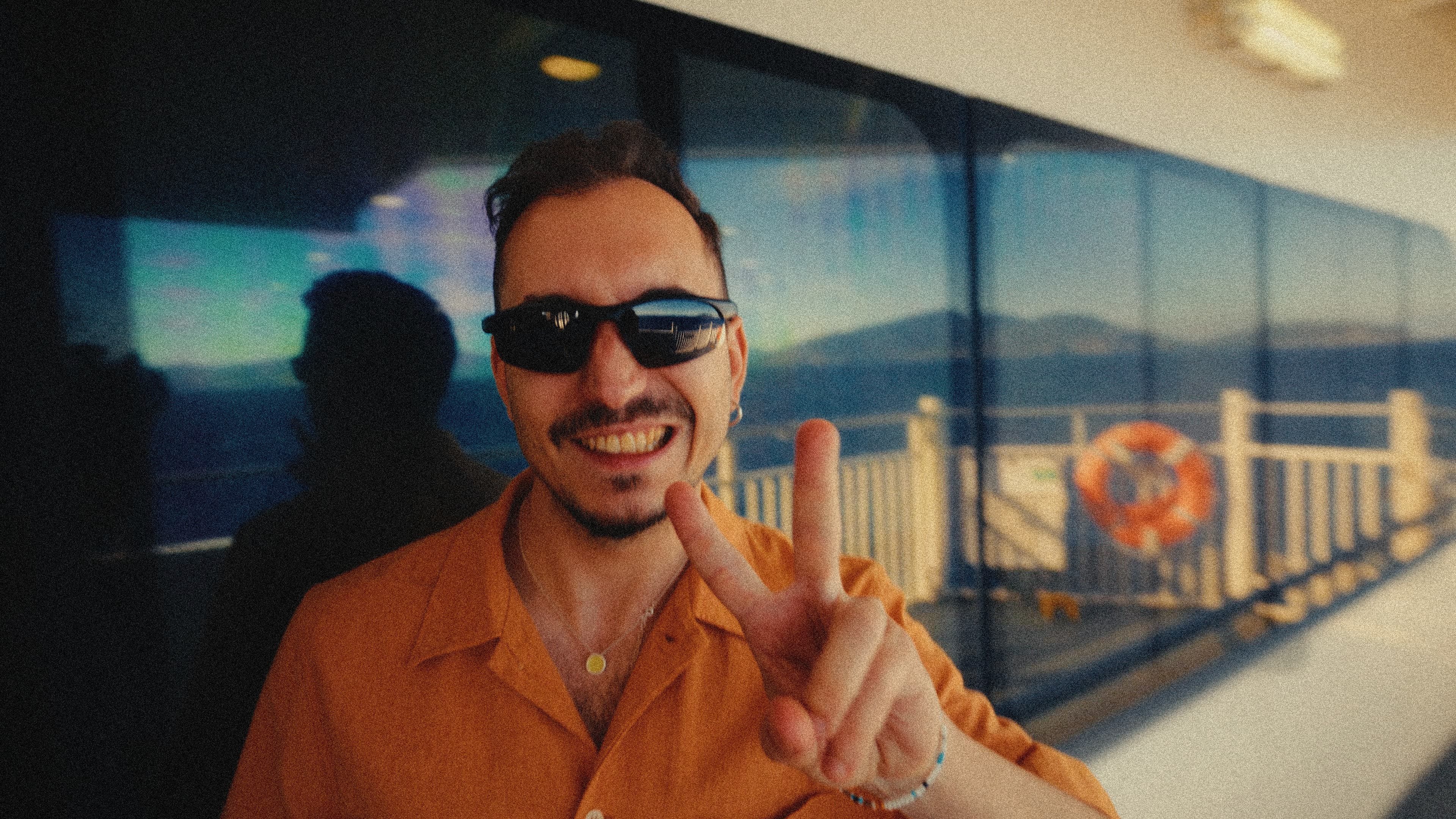 A REBORRN team member smiling and throwing a peace sign on a ferry deck